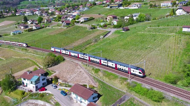Aerial of two Swiss trains crossing in Lavaux vineyard, shot follows one passing over old viaduct. Lake L&radic;&copy;man and the Alps appearing in the background at the end