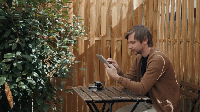 portrait of small business owner at his coffee shop using tablet pc airpods