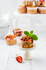 Strawberry chocolate cupcakes muffins on white ceramic stand on wooden  background. Top view.