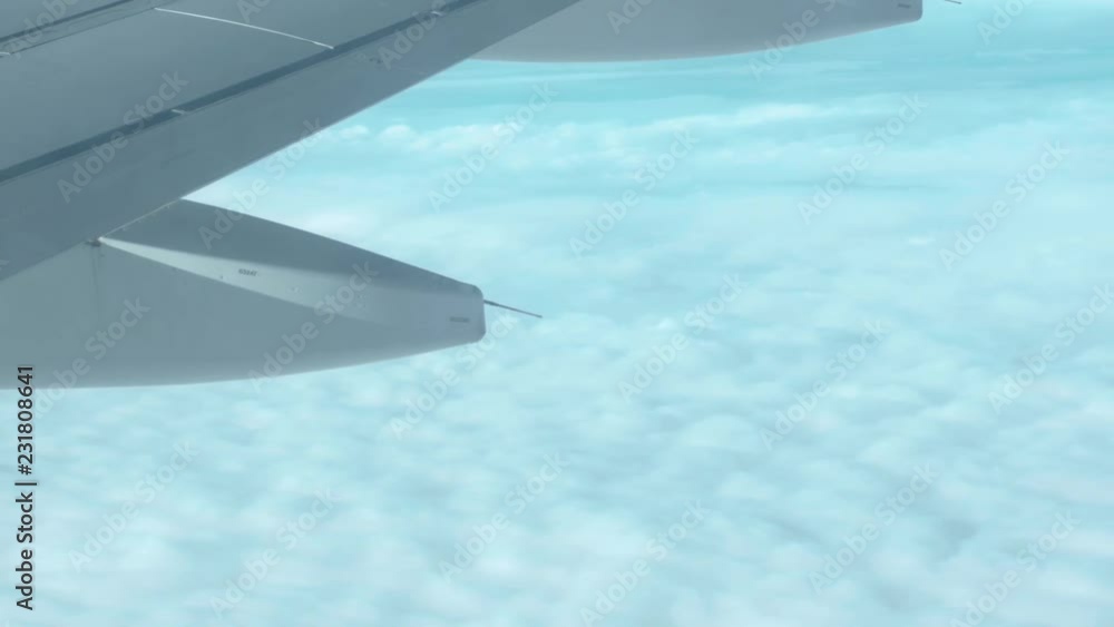 Poster over the clouds view out of an airplane with the plane wing in frame