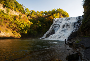 Fototapeta na wymiar Ithaca falls near Cornell University, autumn colors, fly fisherman at the waterfall