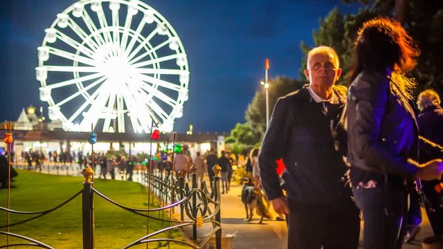 Timelapse of a ferris wheel and a cloudy sky at night in the park, close to the seaside in Bournemouth, England.