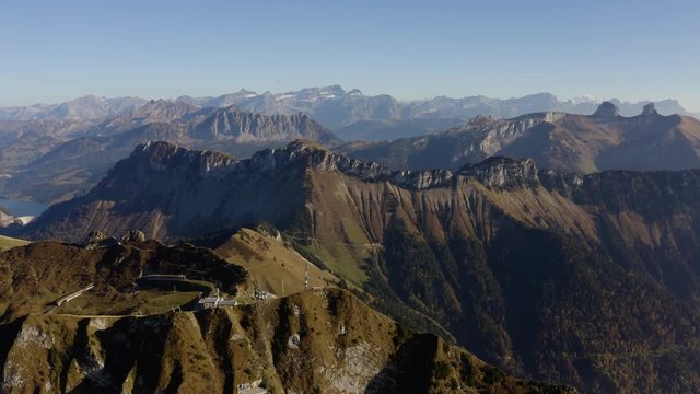 High aerial orbit around summit in the Swiss Prealps (Rochers de Naye, Switzerland). 
Numerous summits in the background, autumn colors