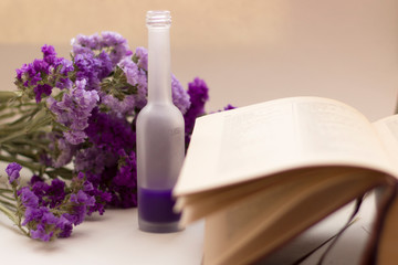 Essential oil in matt bottle on purple flowers blur background.