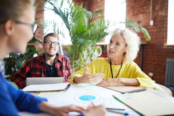 Confident mature professional explaining her opinion about one of organization points to colleague