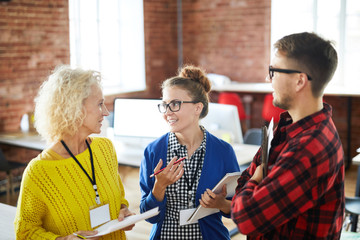 Group of casual colleagues discussing new business trends before seminar or conference
