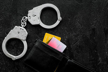 Arrest of cybercriminals, hackers concept. Handcuff near bank card on black background top view space for text