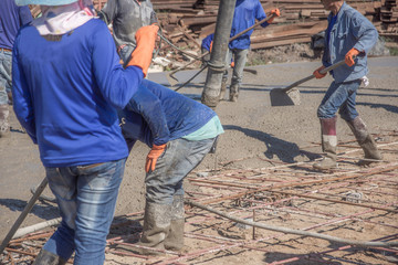 Workers using a wooden spatula for cement after Pouring ready-mixed concrete on steel reinforcement...
