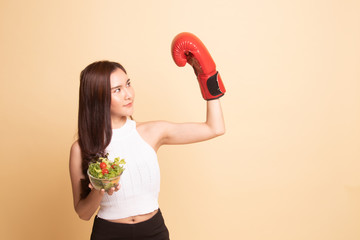 Young Asian woman with boxing glove and salad.