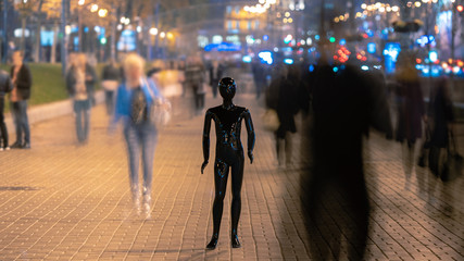 The mannequin stands on the street among the stream of people