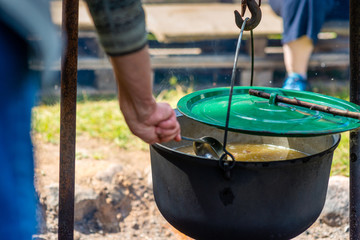 Cooking food in a pot on campfire. Summer camping concept.