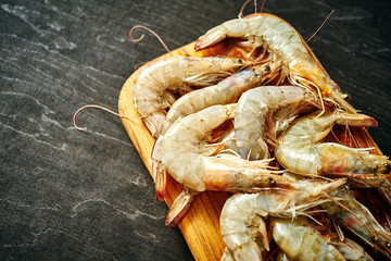 fresh delicious raw tiger prawns on a wooden board on a black wooden table