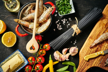 fresh delicious raw tiger prawns in a red pot with parsley, lemon, butter, tomatoes and chili peppers
