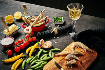 fresh delicious raw tiger prawns in a red pot with parsley, lemon, butter, tomatoes and chili peppers and white wine