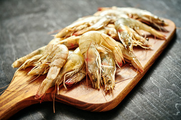 fresh delicious raw tiger prawns on a wooden board on a black wooden table