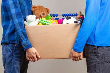 Donation concept. Kids hands holding donate box with clothes, books and toys