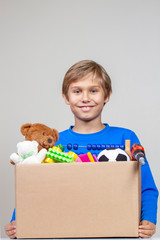 Donation concept. Kid holding donate box with clothes, books and toys
