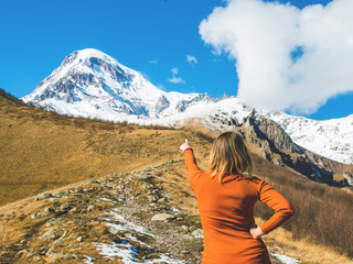 Traveler girl points to the top of the mountain, standing back. Travel lifestyle, holiday vacation concept