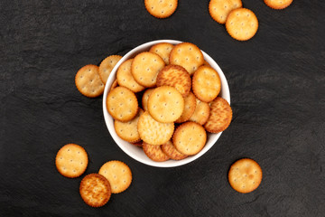 Round salt crackers in a bowl, shot from the top on a black background with a place for text