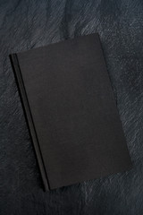 A mysterious black book, shot from the top on a black slate background with a place for text
