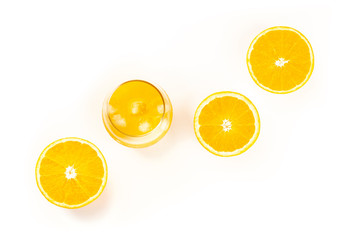An overhead photo of a glass of fresh orange juice with orange halves, shot from the top on a white...
