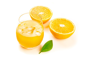 A photo of a glass of fresh orange juice with orange halves and a green leaf on a white background with copy space