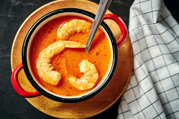 traditional Thai soup with shrimp and coconut milk in a red pot and a spoon