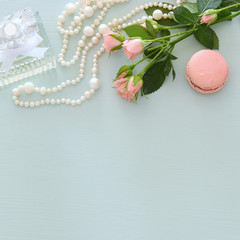 fresh vintage perfume bottle next to colorful macaroon over pastel wooden background.