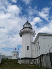 Fototapeta na wymiar Lighthouse of octagonal structure and blue sky.