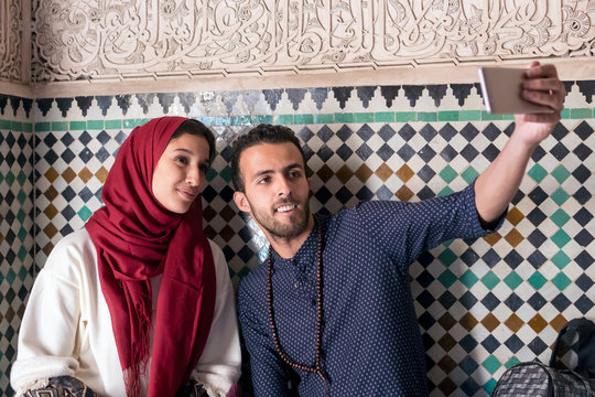 Young Muslim Couple Smiling And Taking Selfie With Smart Phone