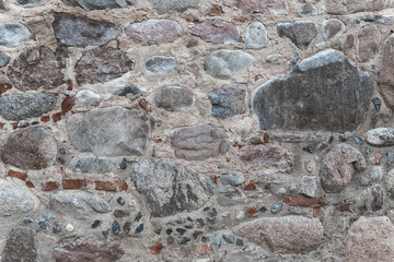 Old stone wall of assorted stones and bricks in the shades of blue and grey