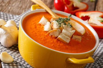 Summer thick cream soup of bell pepper with croutons and herbs close-up on the table. horizontal