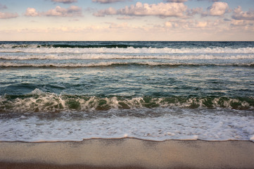 Big breaking Sea wave on a sandy beach on the shore of Sozopol in Bulgaria. Beautiful waves wash the beach with golden sand before sunset. Dramatic scene.