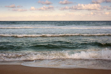 Fototapeta na wymiar Big breaking Sea wave on a sandy beach on the shore of Sozopol in Bulgaria. Beautiful waves wash the beach with golden sand before sunset. Dramatic scene.