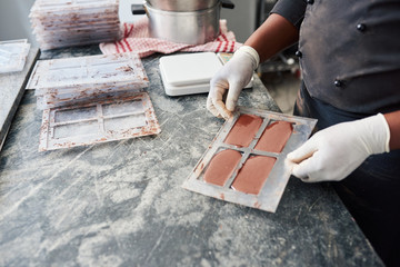 Worker holding a bar mold full of melted chocolate