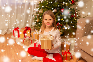 Fototapeta na wymiar christmas, holidays and childhood concept - smiling girl with gift box at home