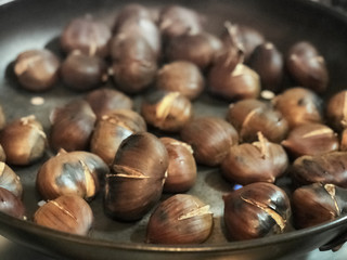 Cooking chestnuts on a pan by flames