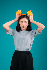 Healthy food. Smiling lovely pinup asian girl holding orange over blue background.