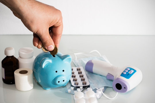 A piggy bank sits on top of pills to pay for rising drug prices. Health care