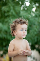Beautiful baby with curly hair in the garden