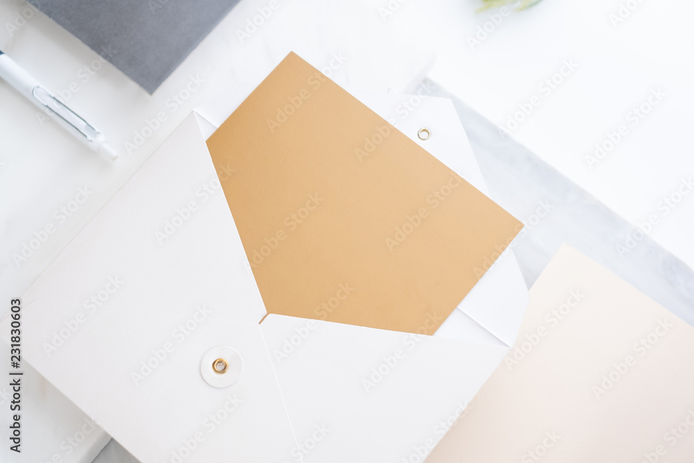 Poster top perspective view of blank golden card in white envelop on two layer step of marble table top.Mock up template for display of design,modern business items.