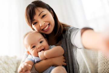 family and motherhood concept - happy young asian mother with little baby son taking selfie