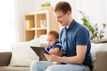 family, technology and fatherhood concept - happy father and little baby son with tablet pc computer at home