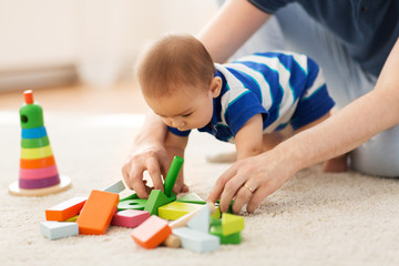 family, fatherhood and people concept - asian baby boy and father playing with toy blocks at home