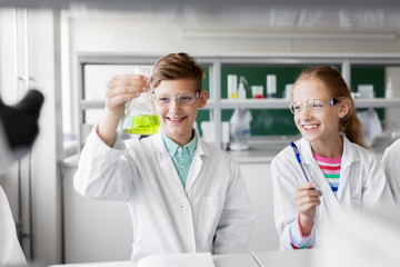 education, science and children concept - kids with test tubes studying chemistry at school...