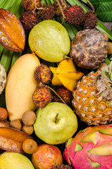 Assorted Thai tropical fruits on a dark wooden rustic background.