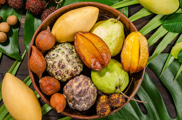 Assorted Thai tropical fruits on a dark wooden rustic background.