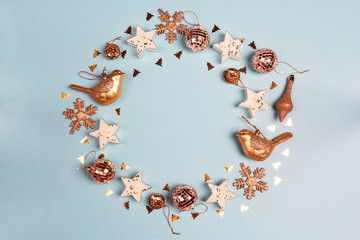 Round frame of golden Christmas decorations wit copy space on blue background. Top view, flat lay.