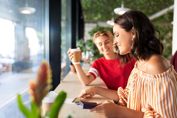 people, cash payment and finances concept - female friends paying by credit card for coffee at cafe