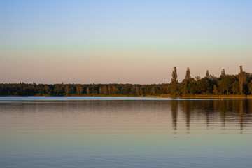 Fototapeta premium Blue lake with cloudy sky, nature series, a lake landscape with reflection from some trees.